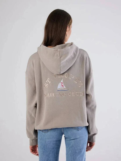Person wearing a beige hoodie with 'St. Thomas Sailing Club' text and logo on the back, standing against a white background.