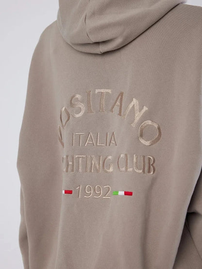 Beige hoodie with embroidered text and flag design on a white background
